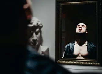Riflesso di un uomo a dorso nudo nello specchio, simbolo visivo di impressione, percezione e identità nel personal branding.