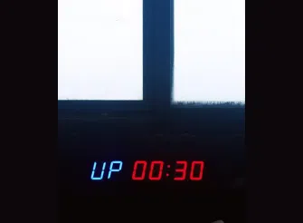 Display digitale con la scritta “UP 00:30” illuminata in rosso e blu, simbolo del tempo frammentato e della perdita di attenzione nella comunicazione contemporanea.