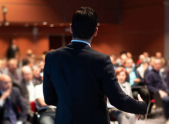 Figura istituzionale di spalle che parla a una platea durante un evento, esempio di personal branding per profili istituzionali.