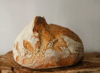 Pagnotta di pane appena sfornata con crosta dorata su un piano da cucina.