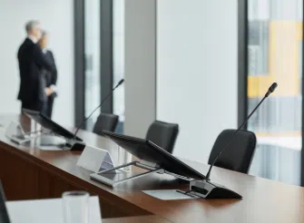 Sala conferenze con microfoni e postazioni vuote, simbolo della voce pubblica dei vertici aziendali e del presidio strategico della comunicazione.