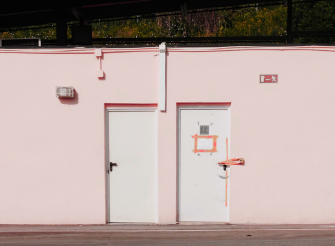 Due porte su una parete rosa, metafora visiva di una transizione di carriera e di una nuova direzione professionale